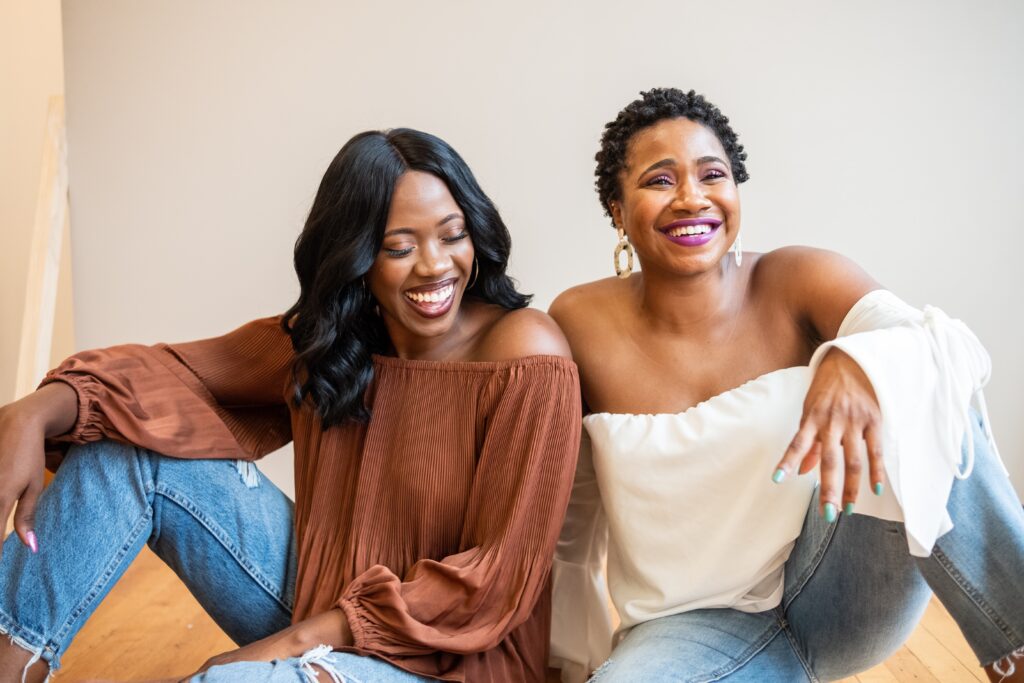 Two Black women dressed casually smiling while seated