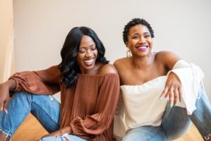 Two Black women smiling while seated