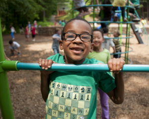 african american boy in foreground with diverse kids in background playing at a playground