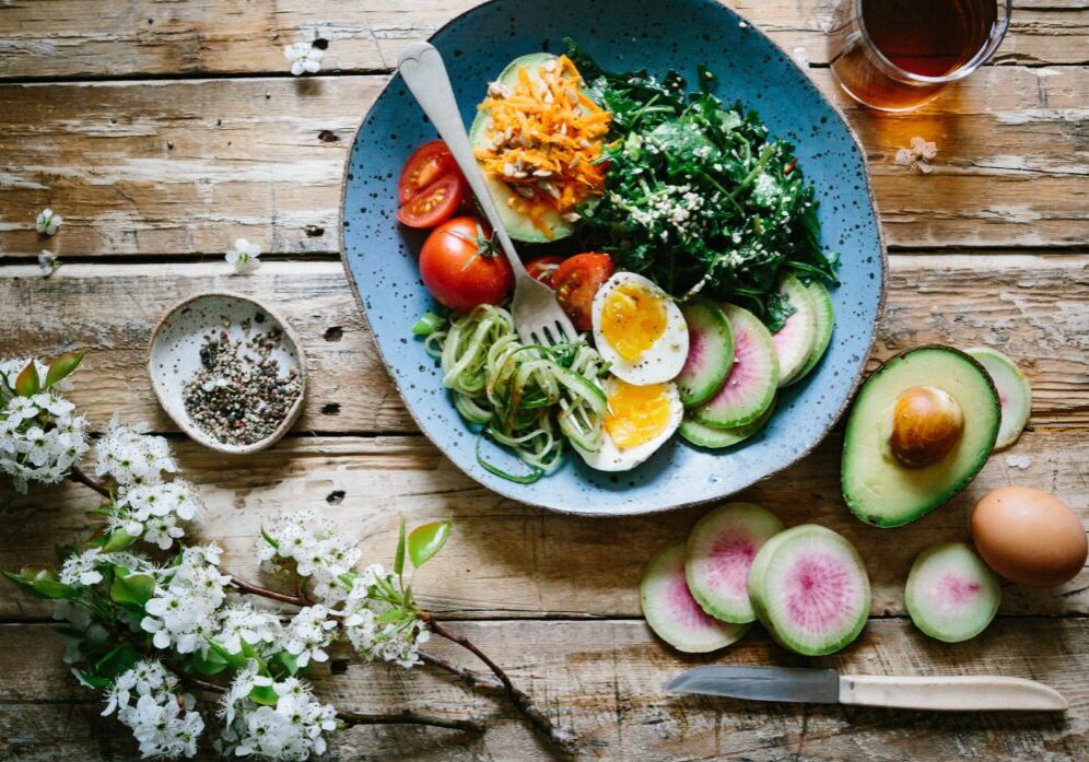 Plate of fresh salad and egg on a wooden table with decorations