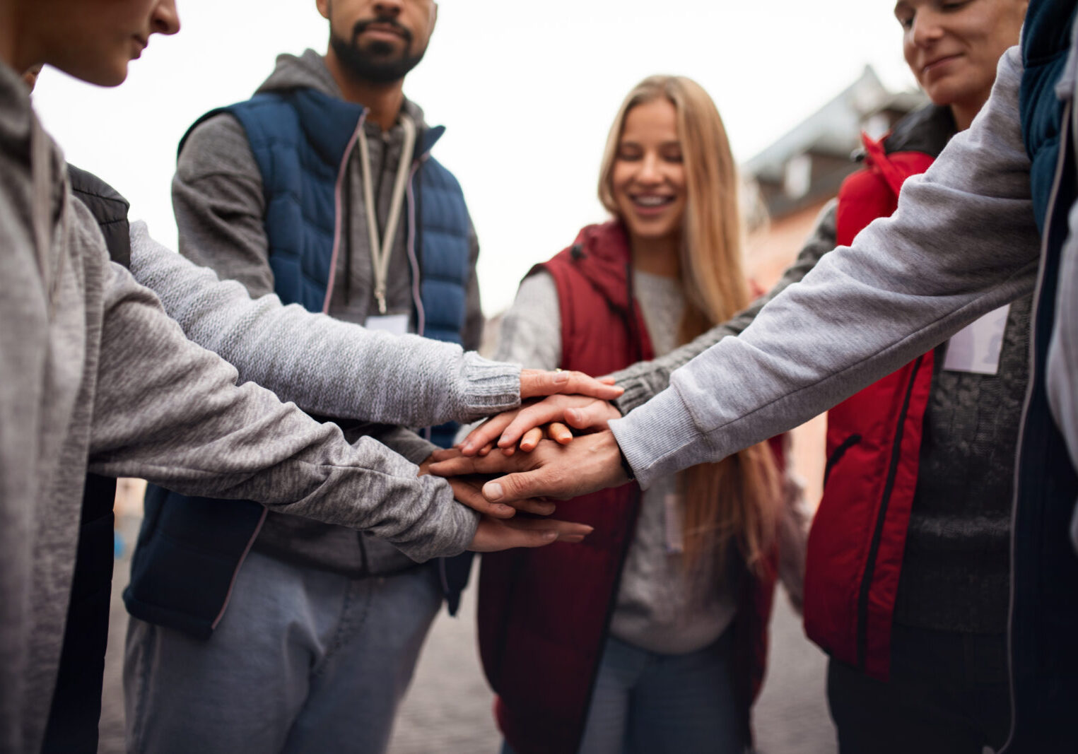 people standing together stacked hands in sign of unity