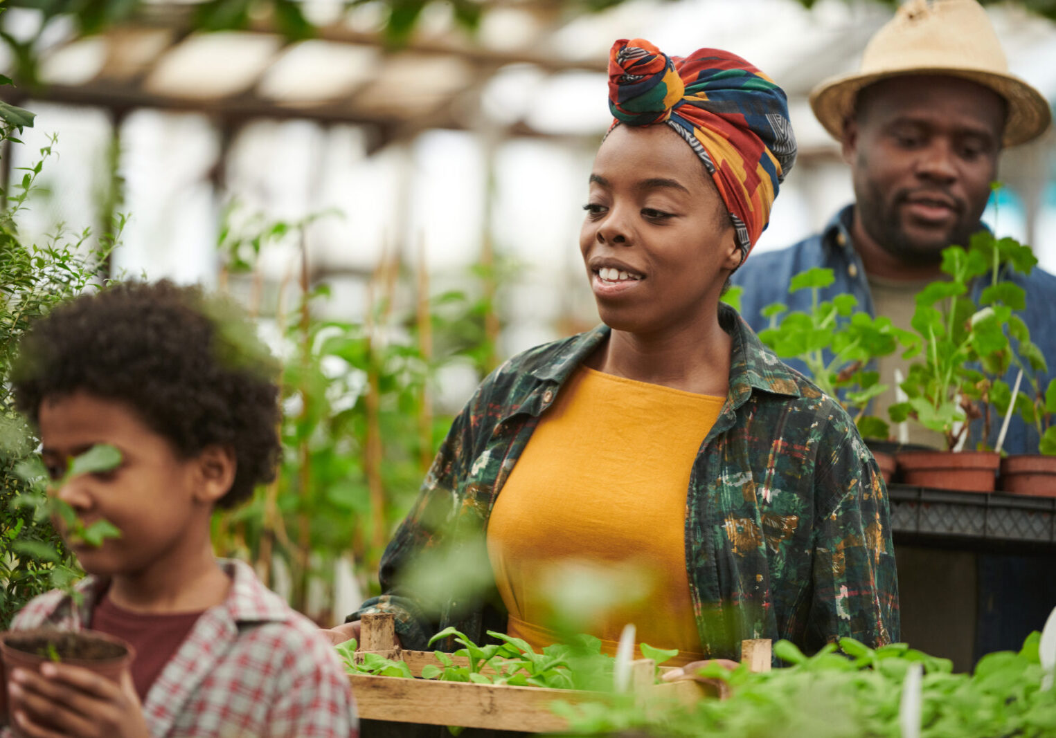 Family of three, man, women, and boy in a green house with vegetation.