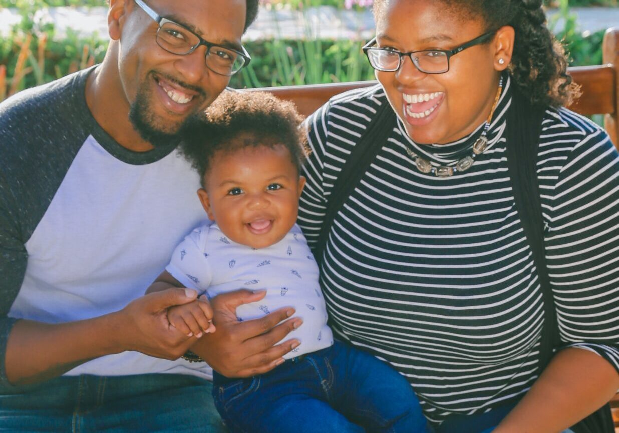 Family of three mother father and toddler boy smiling