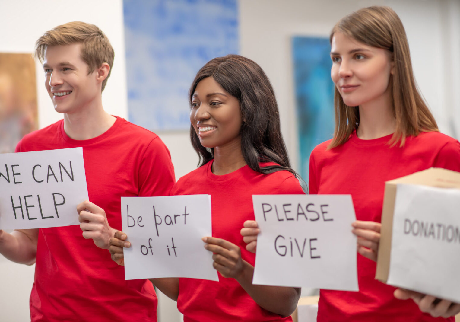 three people with signs promoting giving